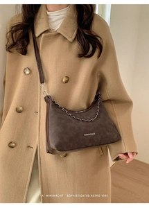 Dettaglio della borsa tote in pelle opaca marrone scuro con catena su cappotto kaki