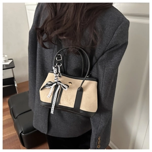 Dettaglio di borsa scamosciata beige con finiture in pelle nera e foulard sul manico