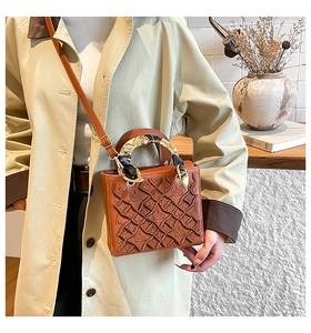 Dettaglio borsa retrò caramello con goffratura floreale e manico decorato con foulard
