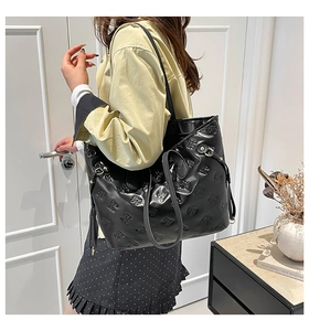 Dettaglio della borsa tote nera con motivi a fiocco goffrati e superficie in pelle lucida
