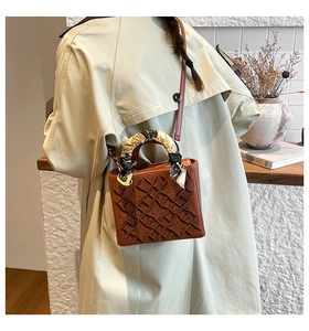Dettaglio della borsa tote marrone retrò con motivo a rilievo e manico con foulard