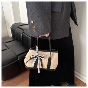 Dettaglio borsa in pelle scamosciata kaki con finiture in pelle nera e fiocco in pizzo