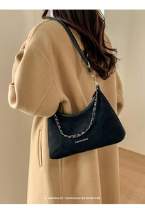 Dettaglio della borsa tote in pelle scamosciata nera con catena d'argento sul cappotto