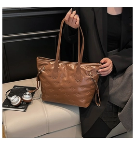 Dettaglio della borsa tote marrone calda con motivi a fiocco goffrati e coulisse laterali