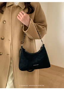 Dettaglio borsa hobo nera con tracolla a catena e logo testuale bianco di moda