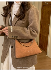 Dettaglio borsa a mezzaluna color caramello con catena metallica e scritte moda