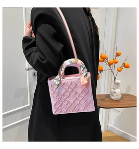 Dettaglio borsa rosa ricamata con manico decorato da foulard e trama a rilievo