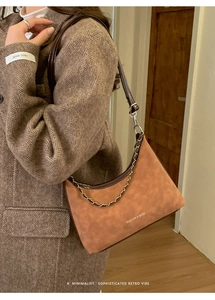 Borsa a mezzaluna vintage marrone con catena dorata mostrata sulla spalla del modello