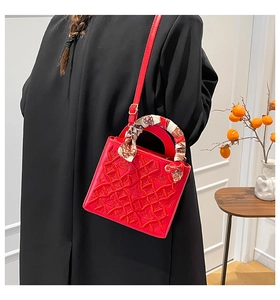 Dettaglio della borsa rossa con rilievo floreale e foulard di seta sul manico