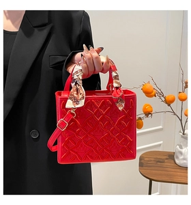 Dettaglio borsa rossa trapuntata con foulard artistico in seta avvolto sul manico