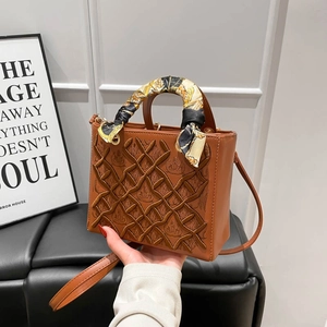 Borsa a mano marrone con ricamo a corona e foulard in seta su sedile in pelle nera