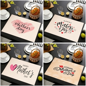 Linen placemats with Mother's Day heart motifs on a wooden table with tableware