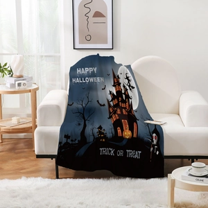 Detail einer Halloween Flanelldecke mit Schloss und Kürbis auf einem weißen Sofa