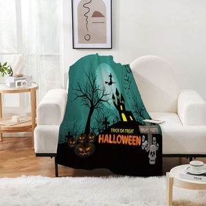 Detail einer weichen Halloween-Vliesdecke mit Schloss- und Kürbisprint auf dem Sofa