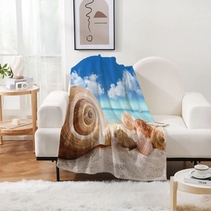 Détail d'une couverture en flanelle à motif océan drapée sur un canapé blanc