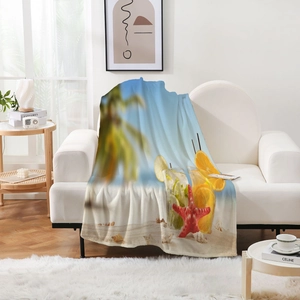Couverture en flanelle avec imprimé plage tropicale disposée sur un canapé blanc chic
