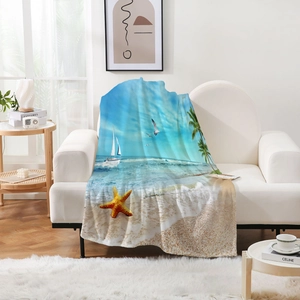 Détail d'une couverture en flanelle aux motifs de plage sur un canapé blanc moderne