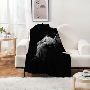 Close-up of realistic cat print on soft black flannel blanket draped over a sofa