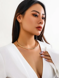 Primo piano di una collana choker minimalista in oro lucido indossata su un modello