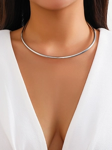 Primo piano di un girocollo d'argento minimalista su una modella in abito bianco