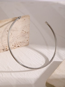 Dettaglio di un choker minimalista argento su pietra con ombre estetiche di finestre
