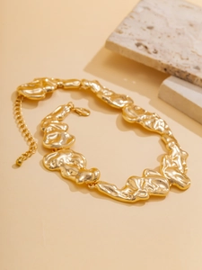 Close-up of irregular liquid gold lava texture on a chunky metallic choker necklace