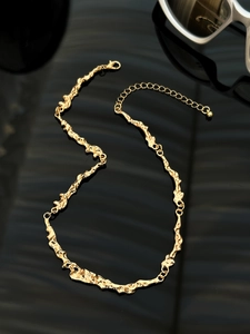 Close-up of gold liquid lava texture choker with irregular organic geometric link design
