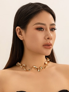 Detailed close-up of a wavy liquid gold-plated metal choker necklace on a model