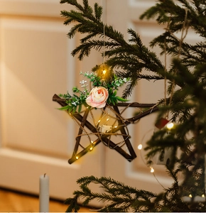 Detail of star-shaped Christmas wreath with LED lights and white roses on a tree
