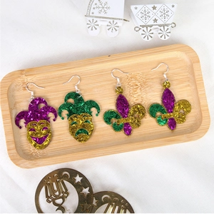 Close-up of glittery Mardi Gras earrings with fleur-de-lis and mask designs