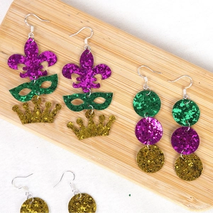 Detail of glitter Mardi Gras earrings with fleur-de-lis, crown and mask icons on wood