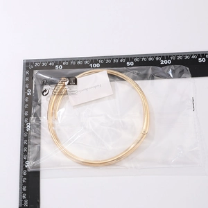 Makroaufnahme des goldenen Feder-Chokers mit Nagel-Design-Details in Verpackung
