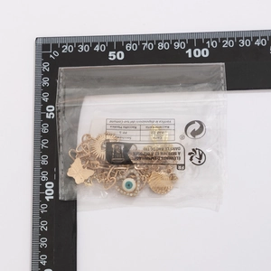 Detailansicht der goldfarbenen Muschel- und Augenanhänger mit Maßstab zur Messung