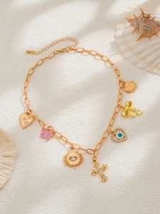 Details einer goldenen Muschelkette mit Schmetterling und Auge der Medusa auf Sand