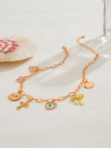 Detail von goldenen Anhängern mit Kreuz, Schmetterling und Muschel an einer langen Kette