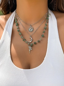 Macro shot of bohemian layered necklace with green gravel beads and fairy charm