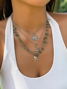 Detail of bohemian layered necklace with sun moon charms and green stone beads