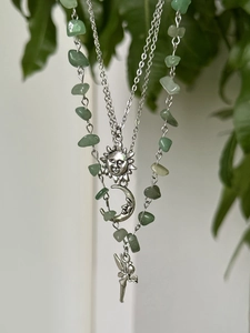 Macro view of Bohemian beaded necklace with green gravel stones and silver mystical charms