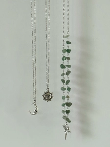 Detailed view of silver-tone necklaces with moon, sun, and green stone charms