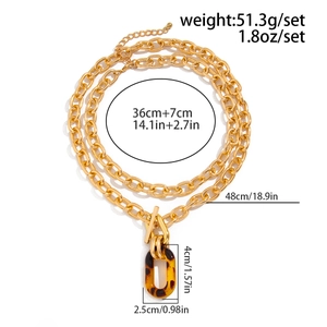 Détail de colliers dorés superposés avec pendentif léopard et fermoir à bascule