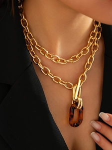 Détail d'un collier à maillons dorés multicouches avec pendentif ovale en résine léopard