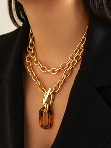 Détail de chaînes en métal doré multicouches avec pendentif ovale en acrylique écaillé