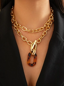 Détail d'un collier doré à deux rangs avec pendentif en acrylique écaillé et fermoir en T élégant