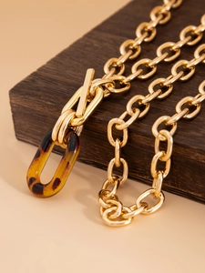 Détail du collier à grosses mailles dorées avec fermoir à bascule et pendentif léopard