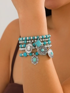 Close-up of bohemian layered turquoise beaded bracelets with silver ethnic charms