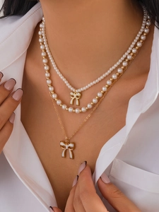 Dettaglio della collana a tre strati con fiocco bianco e perle dorate lucide
