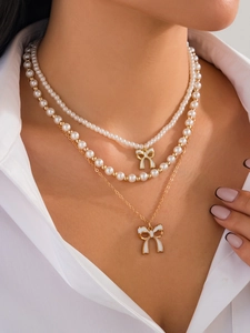 Dettaglio della collana di perle a tre strati con ciondoli a fiocco bianco su modella