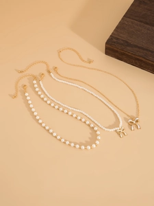Dettaglio di set di collane di perle a strati con eleganti ciondoli a fiocco bianco