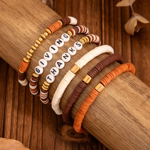 Detail of multi-layer Heishi bead bracelets with GIVING THANKS lettering in autumn colors