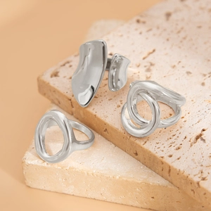 Macro detail of three irregular geometric silver rings on a textured stone surface